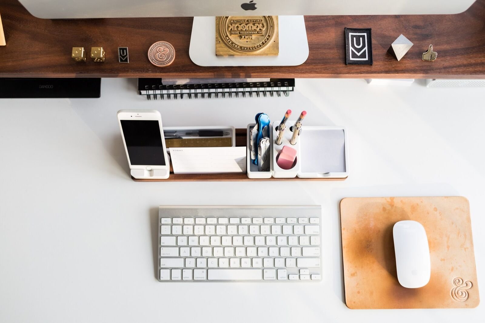 Tidy white desk with a keyboard, mouse and phone, seen from above